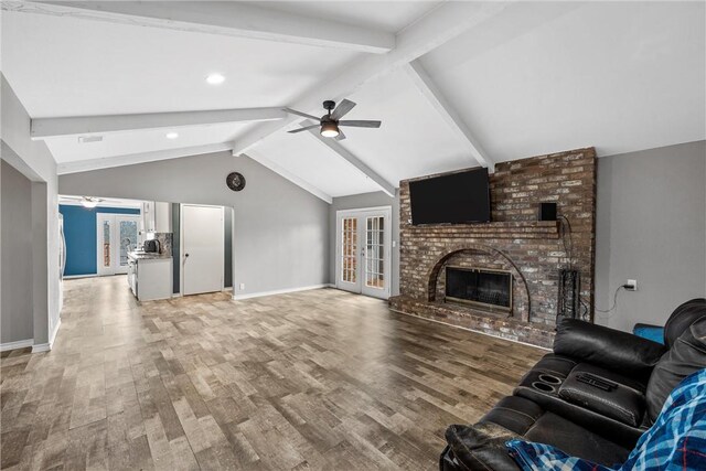 living room featuring a ceiling fan, baseboards, lofted ceiling with beams, and light wood-style flooring