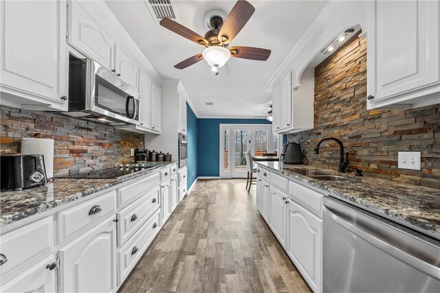 kitchen with crown molding, decorative backsplash, a sink, a ceiling fan, and stainless steel appliances