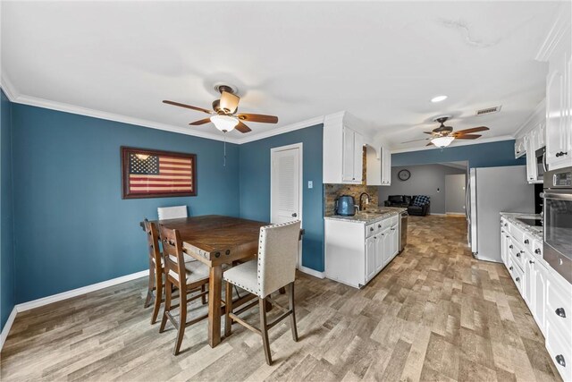 kitchen featuring baseboards, a sink, white cabinetry, and ceiling fan