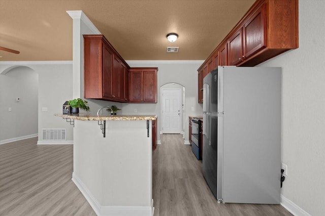 187 Ashland Dr, Woodway, TX 76712 - kitchen featuring light wood finished floors, arched walkways, freestanding refrigerator, a peninsula, and visible vents