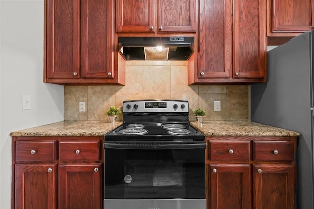 187 Ashland Dr, Woodway, TX 76712 - kitchen featuring decorative backsplash, electric range oven, freestanding refrigerator, reddish brown cabinets, and under cabinet range hood
