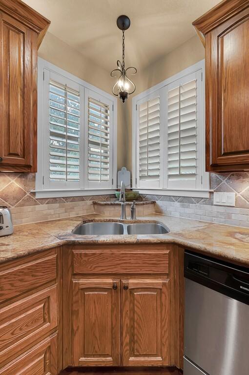 304 Chamberly Rd, Waco, TX 76712 - kitchen with stainless steel dishwasher, backsplash, brown cabinetry, and a sink