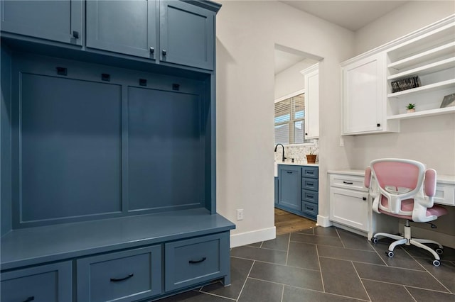 mudroom with dark tile patterned floors, baseboards, and a sink