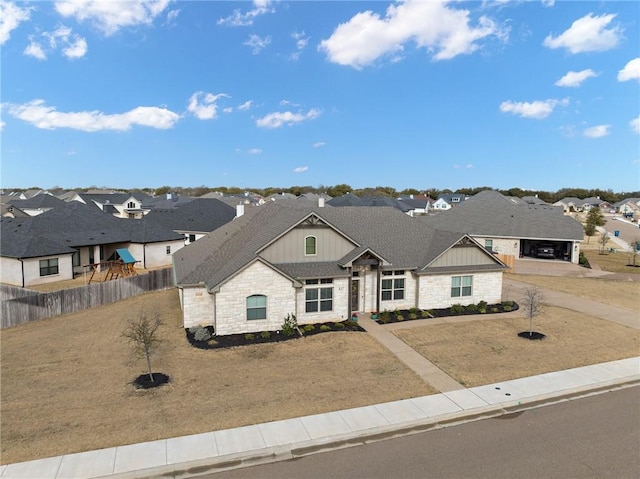 view of front of house with a residential view, stone siding, board and batten siding, fence, and a shingled roof
