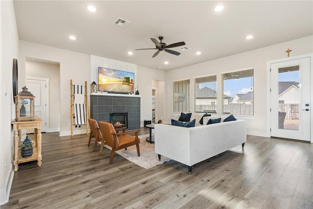 living room featuring ceiling fan, visible vents, baseboards, and wood finished floors