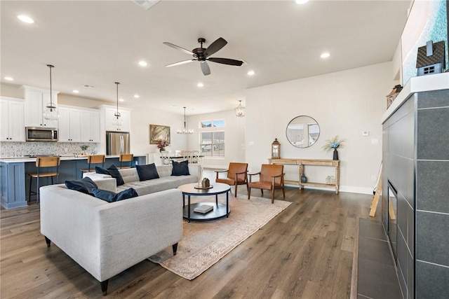 living room with dark wood-style flooring, a ceiling fan, a tile fireplace, and recessed lighting