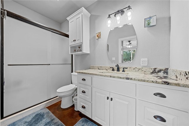 full bath featuring a shower with door, toilet, vanity, and a ceiling fan