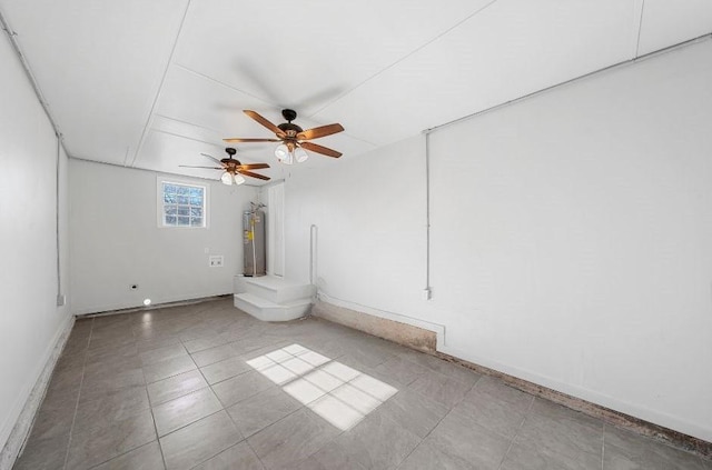 empty room featuring electric water heater, a ceiling fan, baseboards, and light tile patterned floors