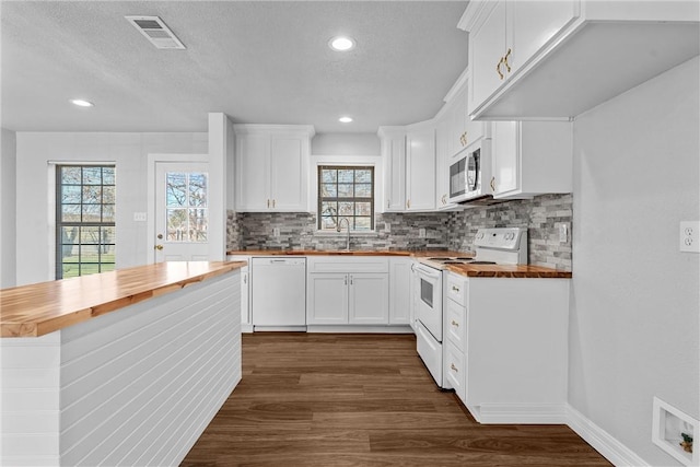 kitchen with wood counters, white appliances, dark wood finished floors, tasteful backsplash, and a textured ceiling