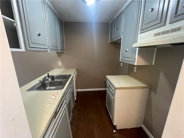 5505 Tennyson Dr, Waco, TX 76710 - kitchen with baseboards, under cabinet range hood, dark wood finished floors, light countertops, and a sink