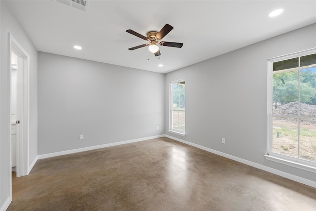 empty room with concrete floors, visible vents, a ceiling fan, and baseboards