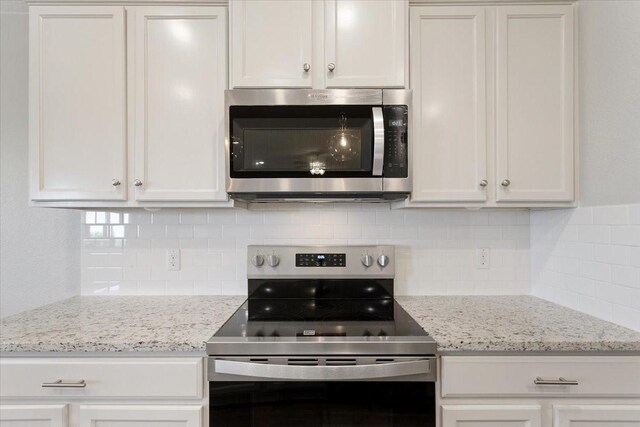 kitchen with backsplash, light stone counters, white cabinets, and appliances with stainless steel finishes