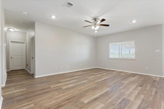 spare room featuring light wood finished floors, visible vents, and ceiling fan