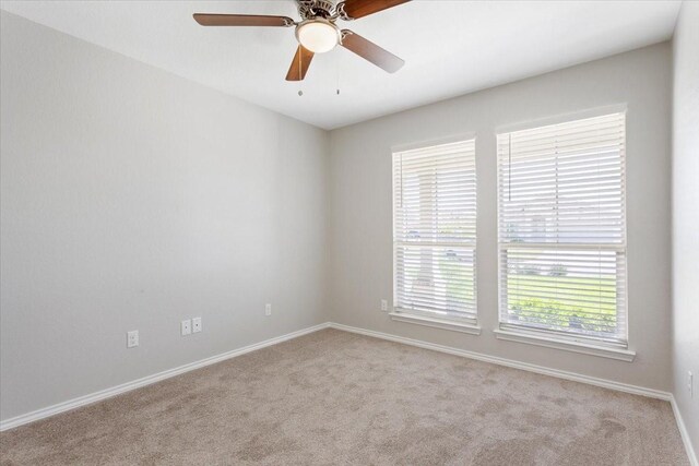 carpeted empty room featuring ceiling fan and baseboards