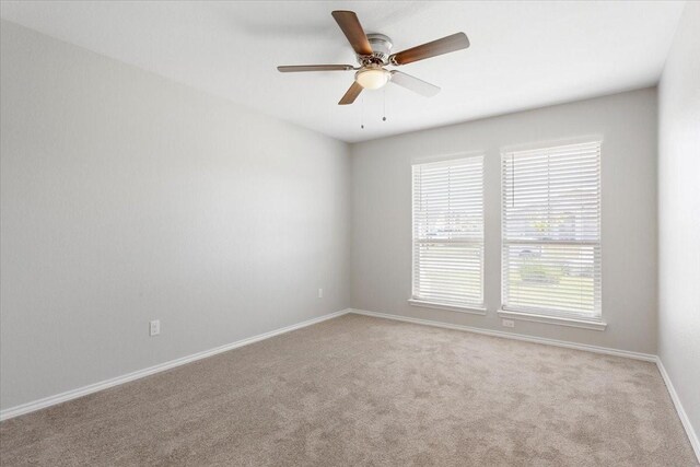 unfurnished room featuring baseboards, light carpet, and ceiling fan