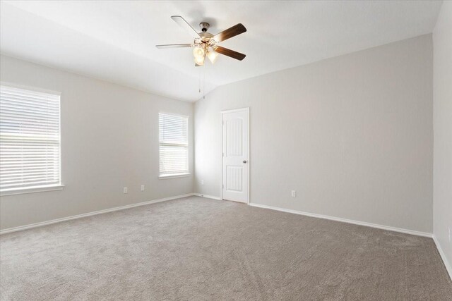 empty room with carpet, vaulted ceiling, baseboards, and a ceiling fan