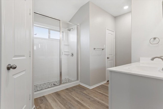 full bathroom with baseboards, a sink, wood finished floors, and a shower stall