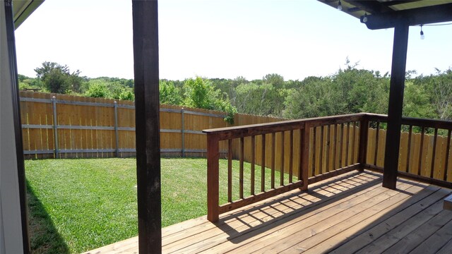 wooden terrace with a yard and fence