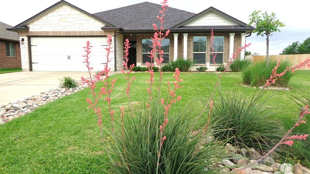 single story home featuring driveway, brick siding, fence, an attached garage, and a front yard