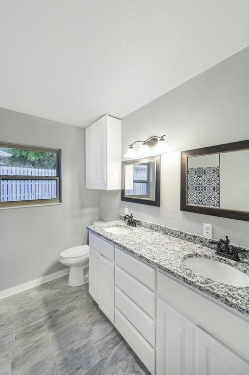 433 Sharron Dr, Woodway, TX 76712 - bathroom featuring double vanity, toilet, baseboards, and a sink