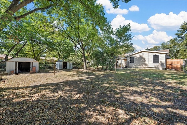 view of yard featuring an outdoor structure, a storage unit, and fence
