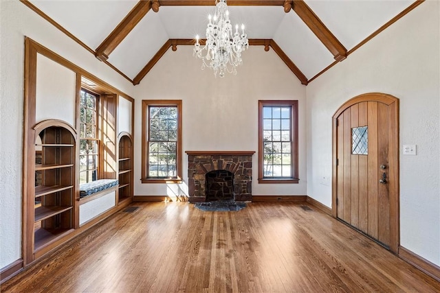 3100 Austin Ave, Waco, TX 76710 - unfurnished living room featuring an inviting chandelier, wood finished floors, a stone fireplace, baseboards, and high vaulted ceiling
