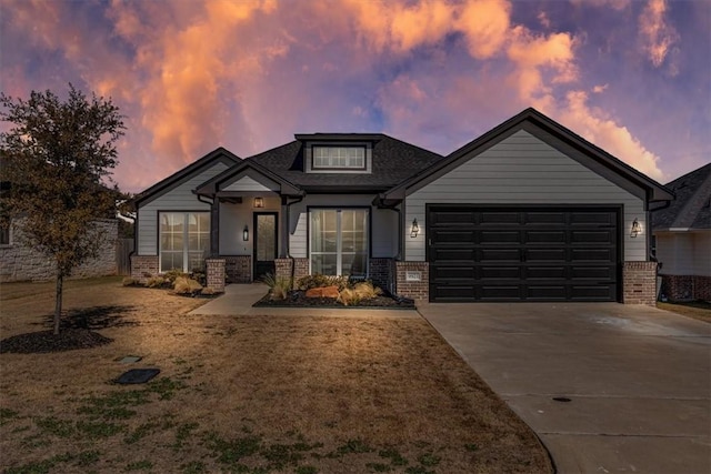 view of front of property featuring a garage, brick siding, driveway, and a yard