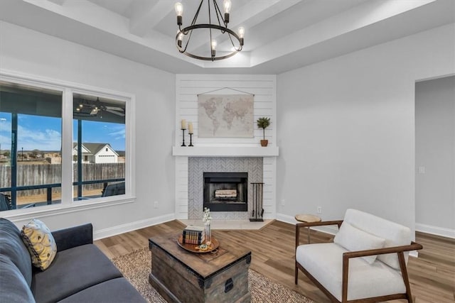 living area with a chandelier, a fireplace, baseboards, and wood finished floors