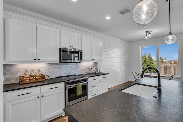 kitchen featuring visible vents, a sink, decorative backsplash, appliances with stainless steel finishes, and white cabinetry