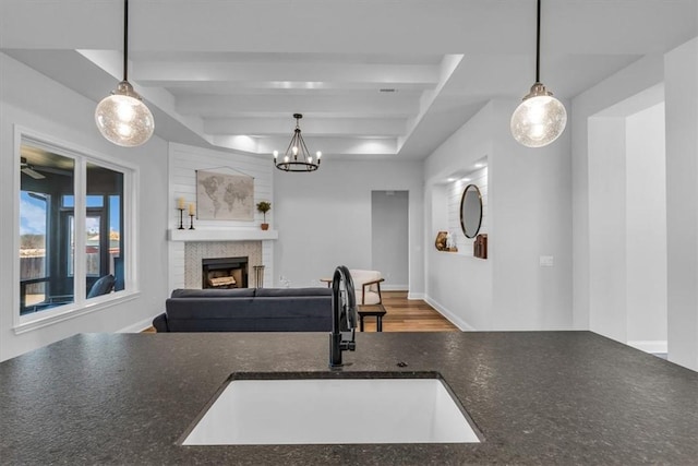 kitchen featuring hanging light fixtures, a fireplace, open floor plan, and a sink