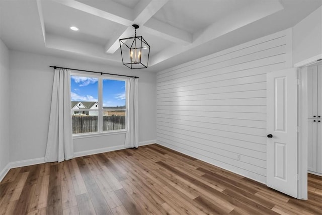 unfurnished dining area featuring a chandelier, coffered ceiling, baseboards, and wood finished floors