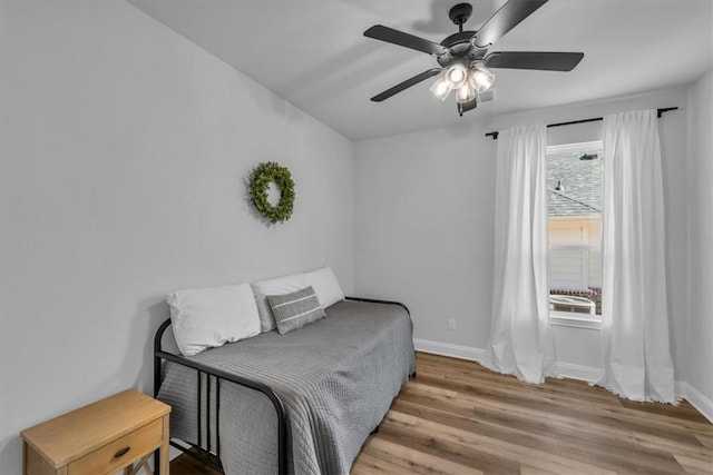 bedroom with a ceiling fan, wood finished floors, and baseboards