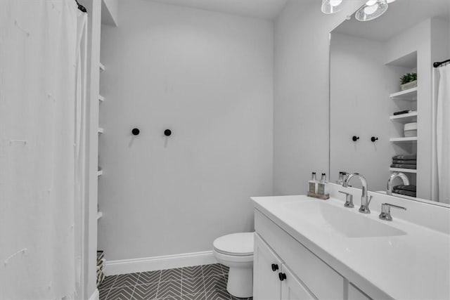 bathroom featuring vanity, toilet, and baseboards
