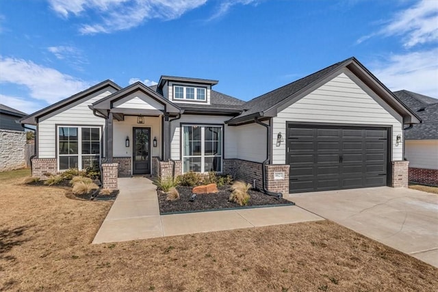 view of front of house with an attached garage, brick siding, driveway, and roof with shingles