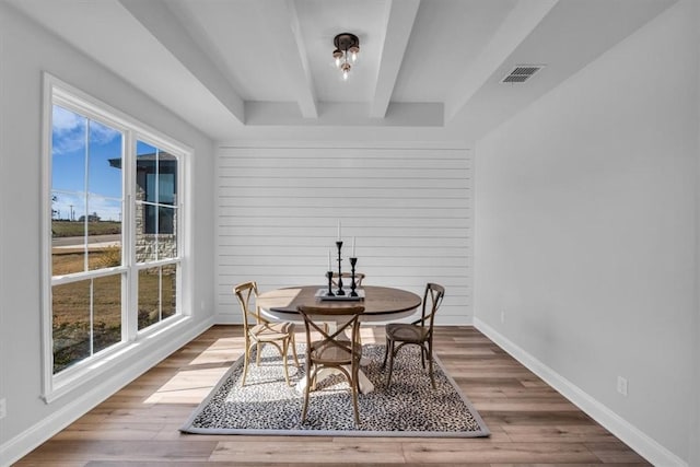 dining room with beamed ceiling, wood finished floors, visible vents, and baseboards