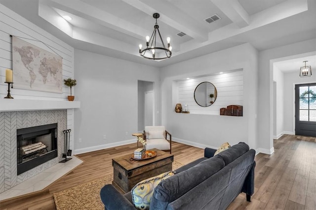 living room with visible vents, wood finished floors, baseboards, and a chandelier
