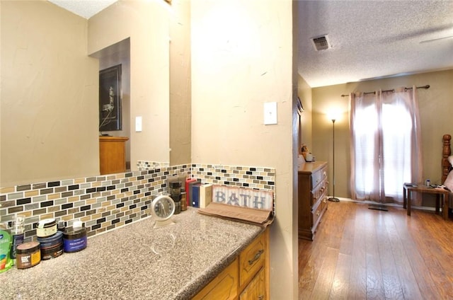 332 Crescent Dr, Hewitt, TX 76643 - kitchen featuring backsplash, brown cabinetry, hardwood / wood-style floors, and a textured ceiling