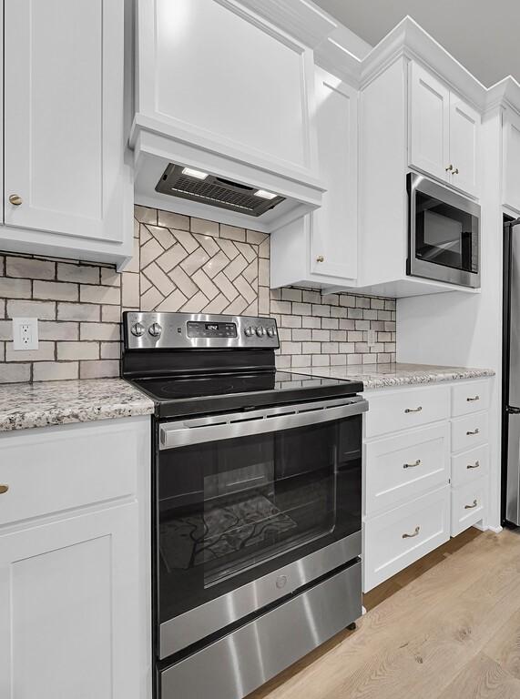 429 Travis Dr, Mcgregor, TX 76657 - kitchen with tasteful backsplash, light stone counters, custom exhaust hood, white cabinets, and stainless steel appliances