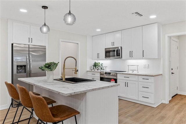4209 Chestnut Rd, Temple, TX 76502 - kitchen with light wood-style flooring, a sink, a kitchen breakfast bar, appliances with stainless steel finishes, and light stone countertops