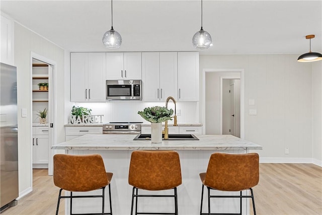 4209 Chestnut Rd, Temple, TX 76502 - kitchen featuring light wood finished floors, a breakfast bar, white cabinets, stainless steel appliances, and a sink