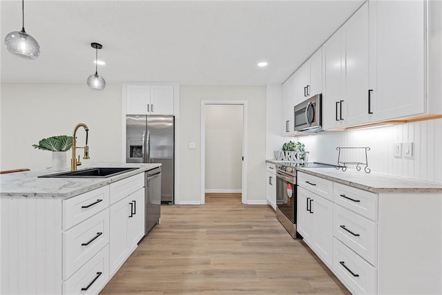 4209 Chestnut Rd, Temple, TX 76502 - kitchen featuring a sink, decorative light fixtures, light stone counters, appliances with stainless steel finishes, and light wood finished floors