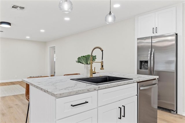 4209 Chestnut Rd, Temple, TX 76502 - kitchen with visible vents, a center island with sink, light wood-style flooring, stainless steel appliances, and a sink