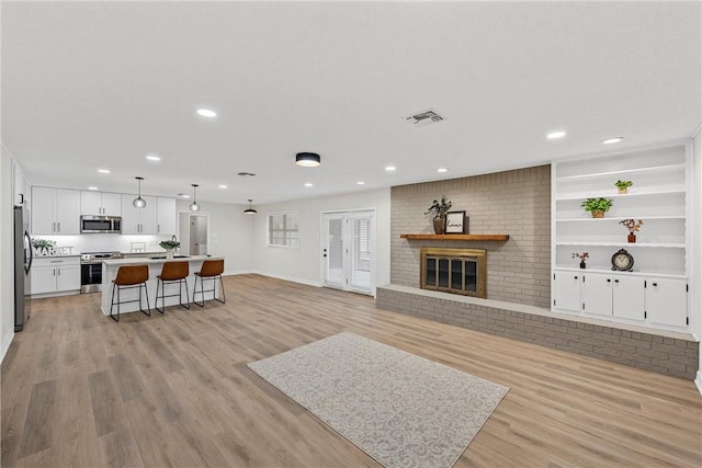 4209 Chestnut Rd, Temple, TX 76502 - kitchen with open floor plan, light wood-type flooring, appliances with stainless steel finishes, a kitchen breakfast bar, and white cabinets