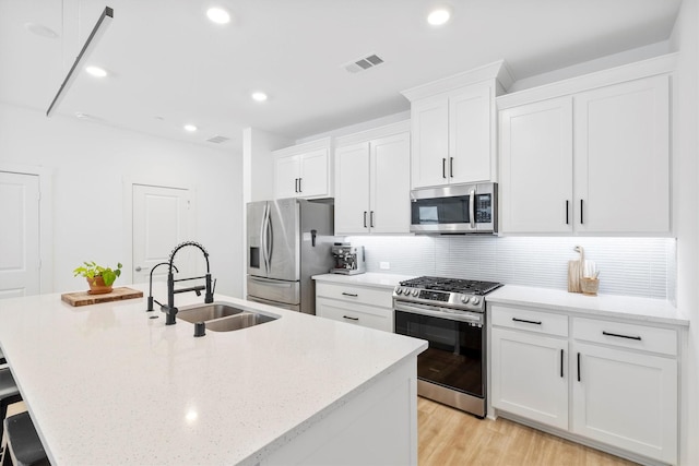 851 Cavitt Ct, Prosper, TX 75078 - kitchen with stainless steel appliances, a sink, an island with sink, backsplash, and white cabinets