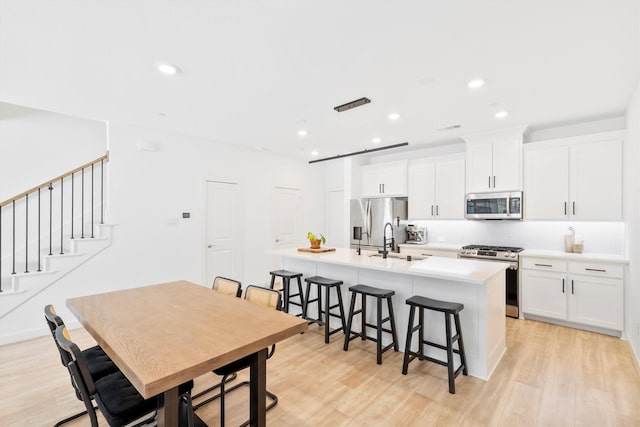 851 Cavitt Ct, Prosper, TX 75078 - kitchen with appliances with stainless steel finishes, a sink, an island with sink, light wood-type flooring, and recessed lighting