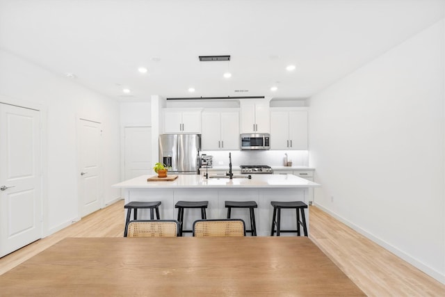 851 Cavitt Ct, Prosper, TX 75078 - kitchen with stainless steel appliances, a sink, a center island with sink, a kitchen bar, and baseboards