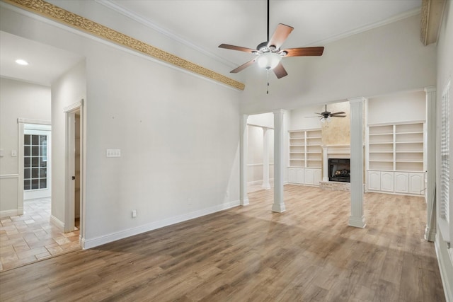 unfurnished living room featuring wood finished floors, ceiling fan, crown molding, and ornate columns