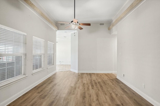 unfurnished room featuring visible vents, ornamental molding, a ceiling fan, wood finished floors, and baseboards