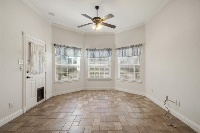 empty room featuring a ceiling fan, baseboards, a fireplace, ornamental molding, and stone finish flooring