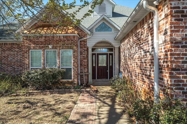 entrance to property with brick siding and roof with shingles